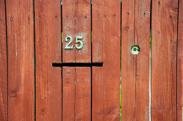 painted wooden fence made of planks with a number and a slot for mail