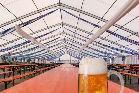 Fertiges und noch leeres Festzelt f&uuml;r das Oktoberfest mit, auf einem Holztisch steht ein Glas Bier