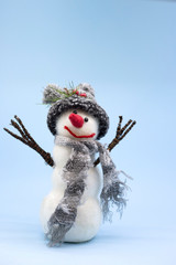 Snowman on a blue background. Snowman in a gray knitted hat and with a gray scarf. Place for text