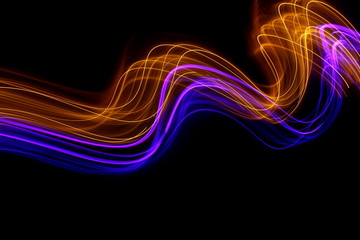 Long exposure photograph of neon gold and purple colour in an abstract swirl, parallel lines pattern against a black background. Light painting photography.
