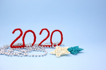 Red inscription 2020 on a blue background next to white and blue rattan star. Christmas atmosphere props