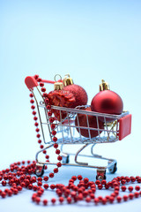 Miniature model shopping trolley with Сhristmas decorations  inside on a blue backgound. Christmas sales and discounts concept