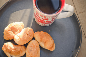 Coffee in a cup and croissants on a plate. Food and drinks. Plate on a wooden background.