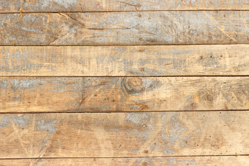The surface of an old wooden board, weathered and faded in the sun.
