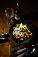 Fresh caesar salad in black plate on dark wooden table. Top view.