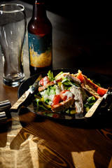 Fresh caesar salad in black plate on dark wooden table. Top view.