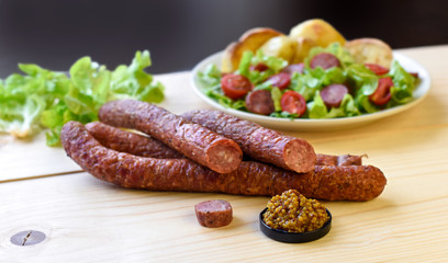 Smoked sausage with vegetables salad on a wooden board