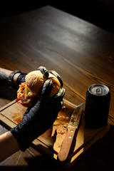 Man holds ready tasty burger in hands in black gloves.