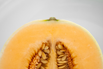 Fresh sweet orange melon on the white plate as a background with a selective focusing. Useful and vitamin-rich food. Vegeterian.