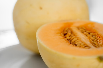 Fresh sweet orange melon on the white plate as a background with a selective focusing. Useful and vitamin-rich food. Vegeterian.