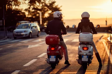 Foto op Plexiglas Couple riding motor scooter on road at sunset. © luckybusiness