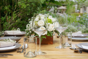 The beautiful arrangement on the wooden table, white roses and ceramic plates. Boho chic wedding table setting.