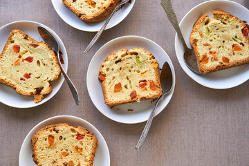 Slices of cake with candied fruit on white plates 