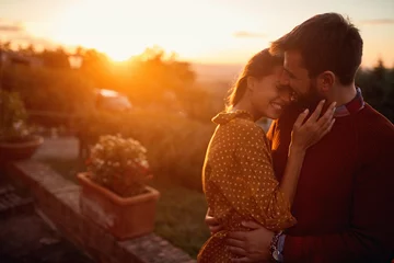 Fotobehang romantic man and woman at sunset. Smiling man and woman is enjoying sunset © luckybusiness