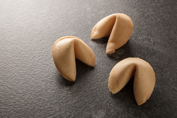 Fototapeta na wymiar three chinese fortune cookies on a dark gray background with copy space, selected focus, narrow depth of field