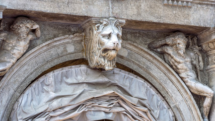 Sculpture on facade of old building, Venice, Italy. Head of lion and human statues in exterior decoration. Detail of the ornate vintage house. Antique style of Italian architecture.