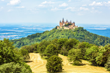 Landscape with Hohenzollern Castle, Germany. This fairytale castle is a famous landmark near Stuttgart. Scenic panorama of mount Burg Hohenzollern and fields. Scenery of Swabian Alps in summer.