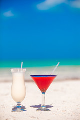 Two cocktails: pina colada and strawberry margarita on white sand beach