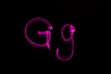 Long exposure photograph of  the letter g in pink neon color, in upper case and lower case,...
