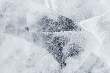 Close-up of snow on cracked and thin layers of ice in the winter. Simple and minimal full frame abstract background in black and white. Copy space.