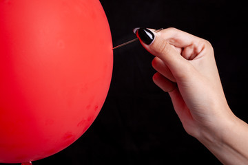 burst red balloon with a needle - danger concept