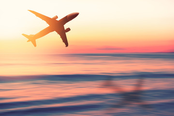 Airplane flying over tropical beach with smooth wave and sunset sky abstract background.