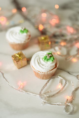 New Year's sweets on a marble table. Christmas cupcakes decorated with mastic and cream