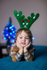 Fototapeta na wymiar happy smiling boy in a New Year costume of a deer celebrating Christmas and New Year