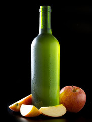 Bottle of very cold cider with apples with black background - image