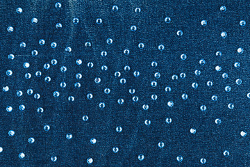 Fashion background with blue rhinestones on denim. Milky way inlay.