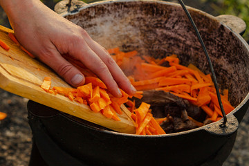 Chef preparing lunch. Stainless steel iron pot on an induction cooker which prepares the meat with...
