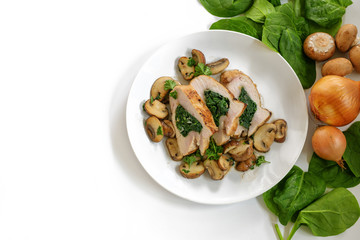 chicken breast fillet with spinach filling, mushrooms, onion and parsley garnish on a plate, some raw ingredients, white background with large copy space, high angle view from above