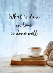 what is done in love is done well - inspiration motivation quote. Cup of tea, sweater and old books. cozy winter still life with tea cup on windowsill. frozen window, Christmas season. soft focus