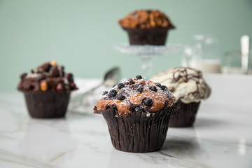 Muffin Auswahl mit Blaubeeren, Walnuss, Haselnuss und Weiße Schokolade mit Milch und Zucker für Kaffeepause auf Marmor Tisch und Grün Hintergrund