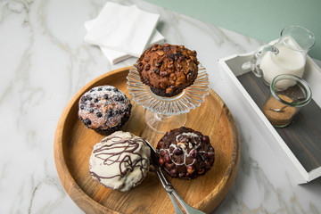 Muffin Auswahl mit Blaubeeren, Walnuss, Haselnuss und Weiße Schokolade mit Milch und Zucker für Kaffeepause auf Marmor Tisch und Grün Hintergrund