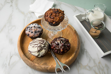 Muffin Auswahl mit Blaubeeren, Walnuss, Haselnuss und Weiße Schokolade mit Milch und Zucker für Kaffeepause auf Marmor Tisch und Grün Hintergrund