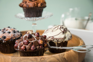 Muffin Auswahl mit Blaubeeren, Walnuss, Haselnuss und Weiße Schokolade mit Milch und Zucker für Kaffeepause auf Marmor Tisch und Grün Hintergrund