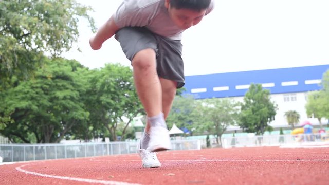 fit and confident fat boy in starting position ready for running. kid athlete about to start a sprint looking forword. exercise concept