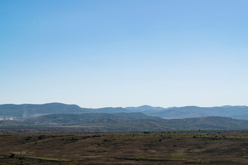 Crimean landscape. Steppe in the foreground and mountains covered with fog in the background.