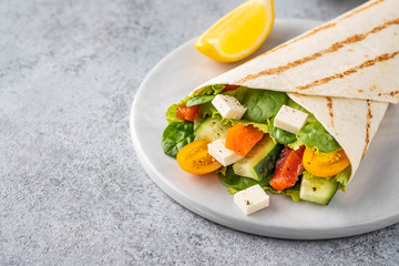 Wrap sandwich, roll with fish salmon, vegetables and cheese. Grey background. Close up.