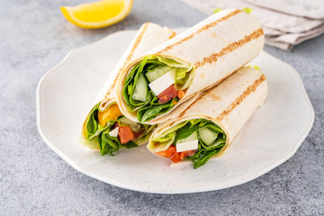 Wrap sandwich, roll with fish salmon, vegetables and cheese. Grey background. Close up.