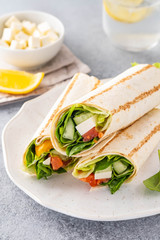 Wrap sandwich, roll with fish salmon, vegetables and cheese. Grey background. Close up.
