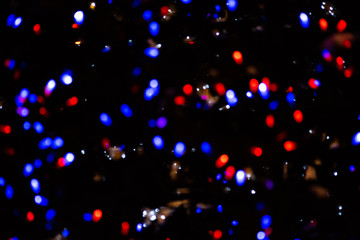 Blurred background with small blue and red bokeh of a festive garland
