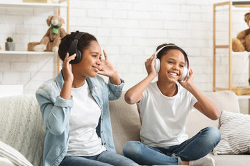 Schoolgirls listening to music with wireless headphones and dancing