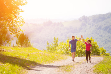 jogging couple giving high five to each other on sunny day at nature
