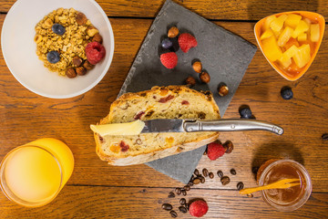 Petit déjeuner varié avec pain aux fruits secs et céréales jus d'orange frais miel salade de fruits grains de café et fruits rouges avec un bol de céréales et un couteau à beurre pour tartiner