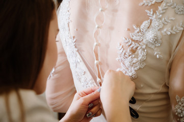 Woman with dressmaker are making final touch in bridal clothing shop.