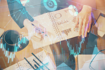 Double exposure of hands making notes with forex chart huds. Stock market concept.