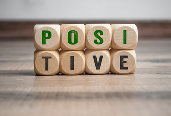 Cubes and dice showing the word positive in green colour on wooden background