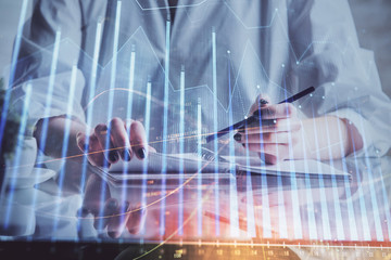 Financial forex graph drawn over hands taking notes background. Concept of research. Double exposure